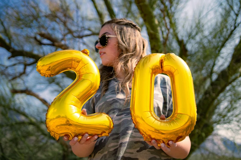 a woman with an air filled gold number balloons