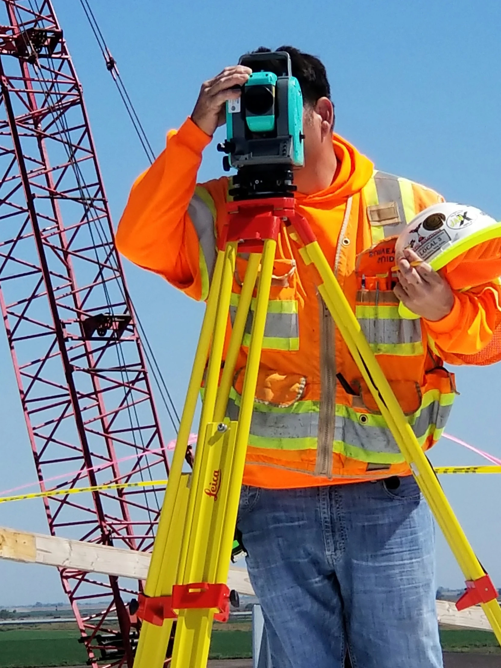 a construction worker uses a digital camera to record the height of a construction crane