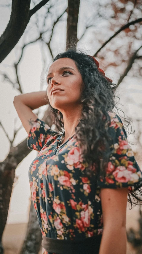 a woman stands in front of a tree and looks up