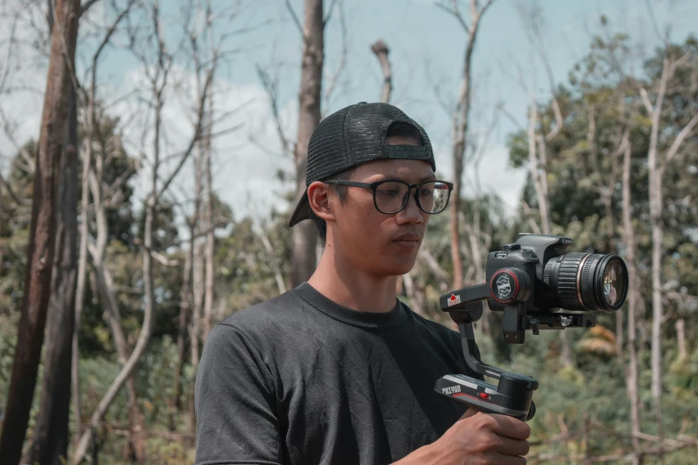 a man in glasses and a cap holding a video camera