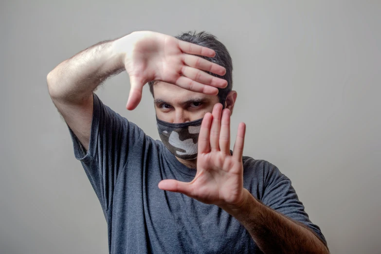 a man wearing a face mask while holding his hands up