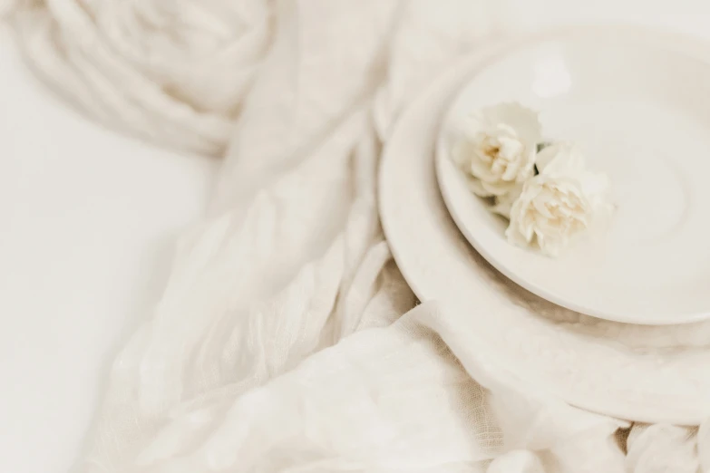 two plates with flowers on one of them and a white scarf around the other