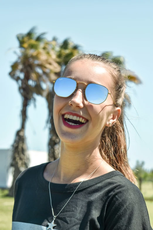 a pretty young woman wearing sunglasses and smiling