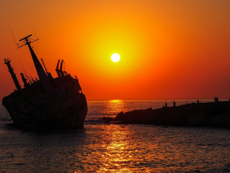 a large boat is sailing in the ocean at sunset