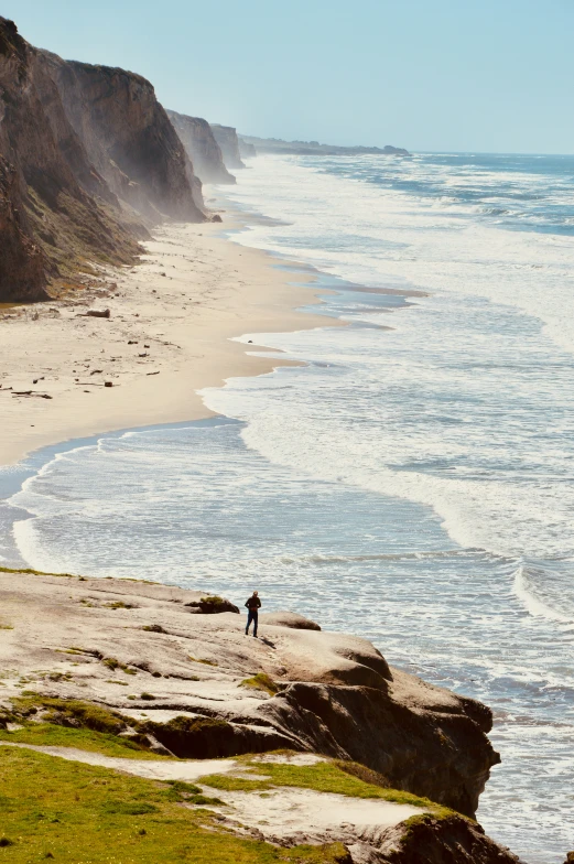 a person is standing at the edge of a rocky shore line