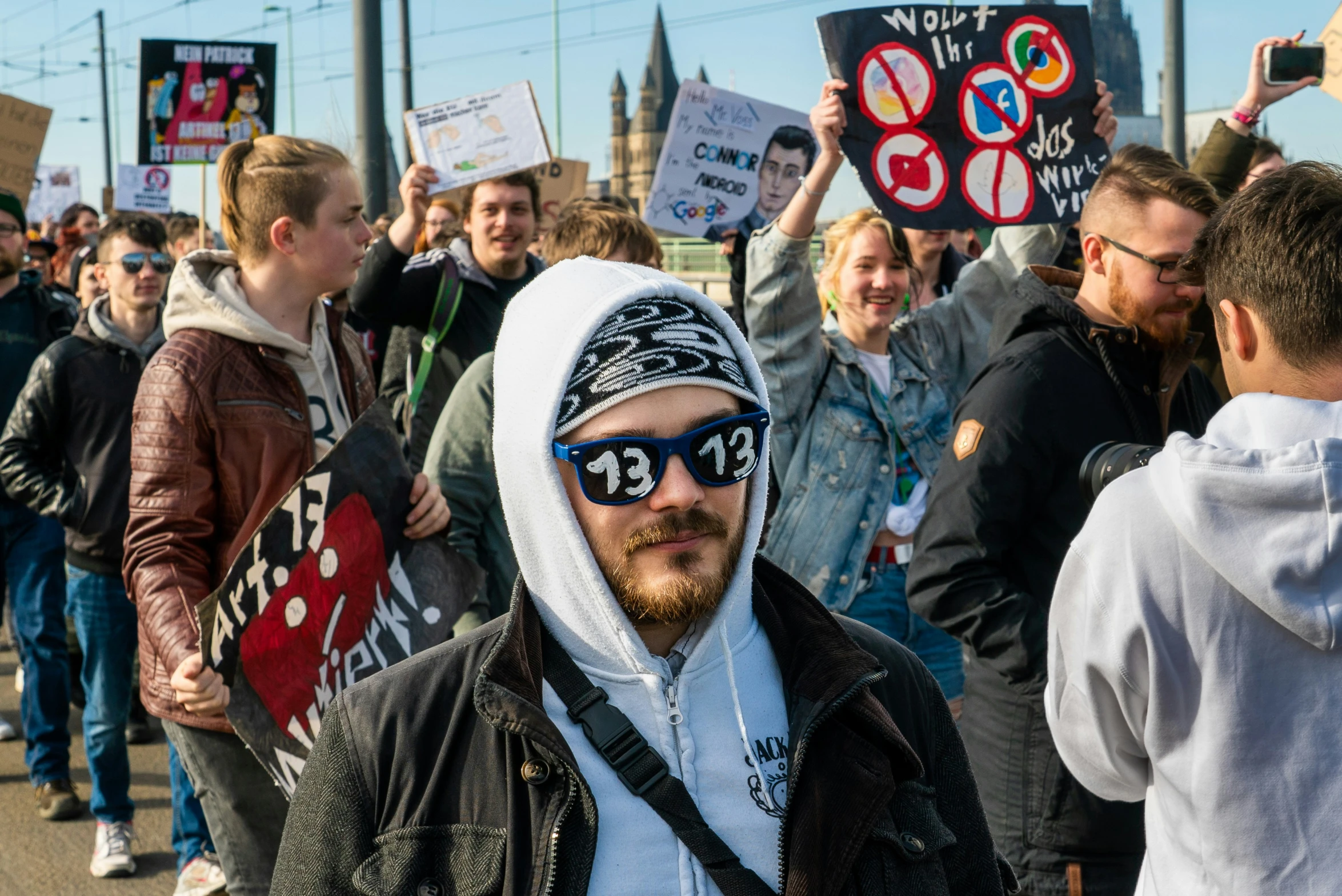 a man with sunglasses on his head and hood holding up signs