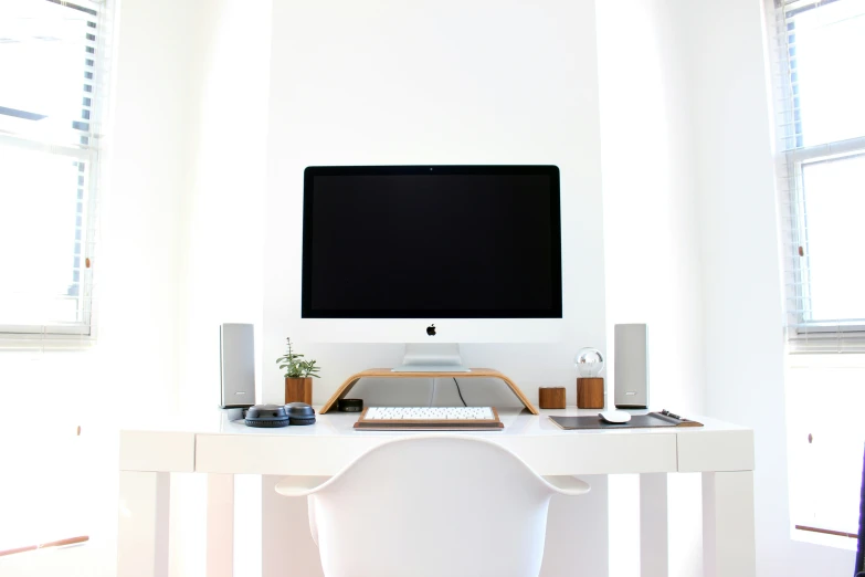 the table is made of a white wood and has a desktop computer on top