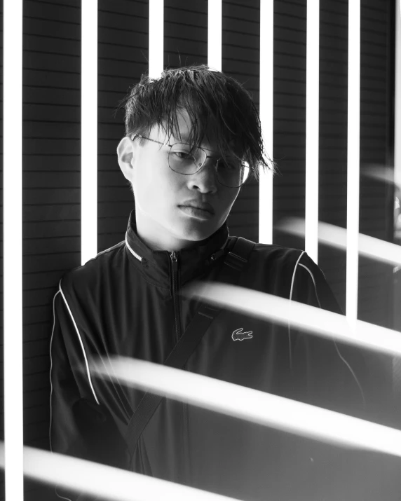 a young man standing behind bars in a black and white po