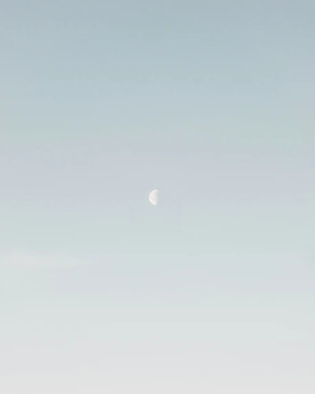 a small jetliner flying through the sky under a moon