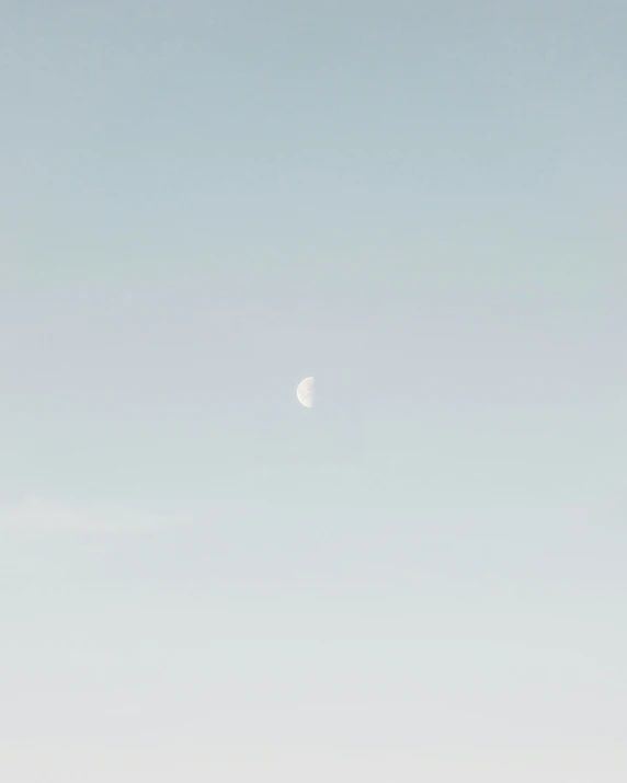 a small jetliner flying through the sky under a moon