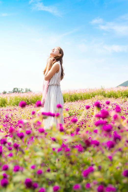 a woman stands in the middle of a field of flowers