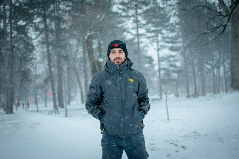 a man in a gray jacket standing on a snow covered slope