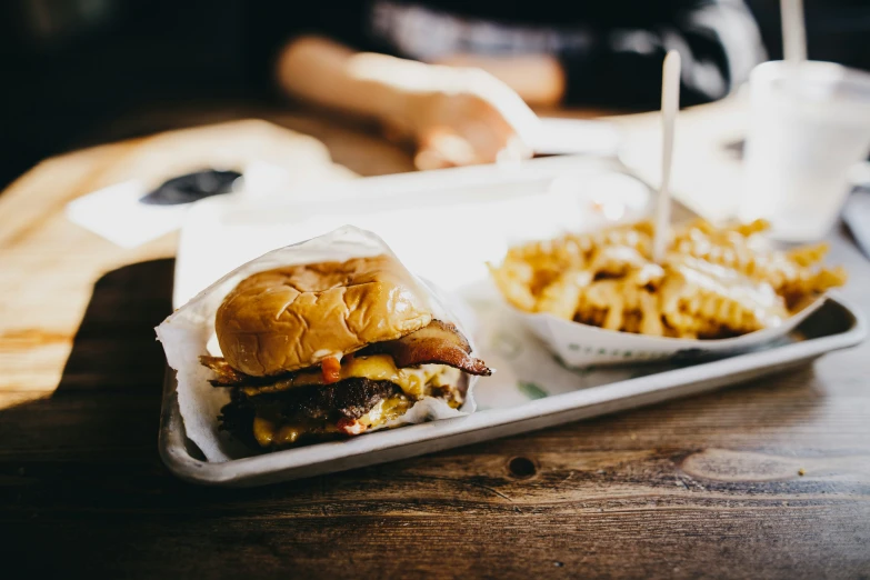 a tray topped with a hamburger and waffle fries