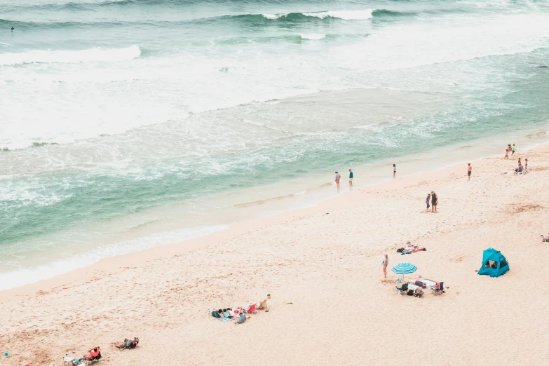 people are walking on a beach with the ocean in the background