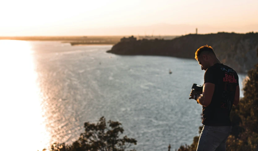 a man is standing on top of a hill looking at the ocean