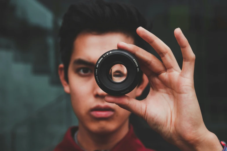 man holding up a camera lens to take a po