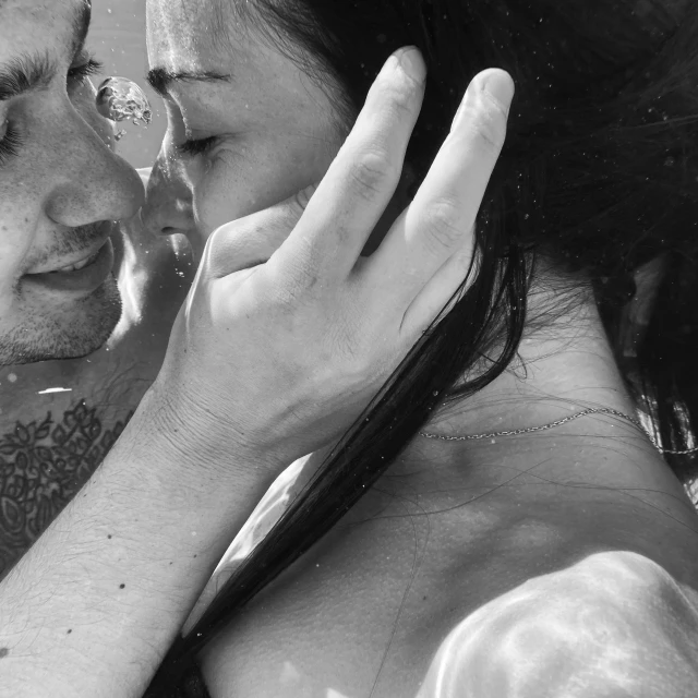 man and woman under water touching foreheads