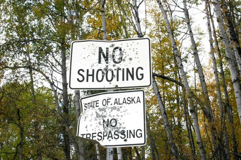 a street sign and another sign near some trees