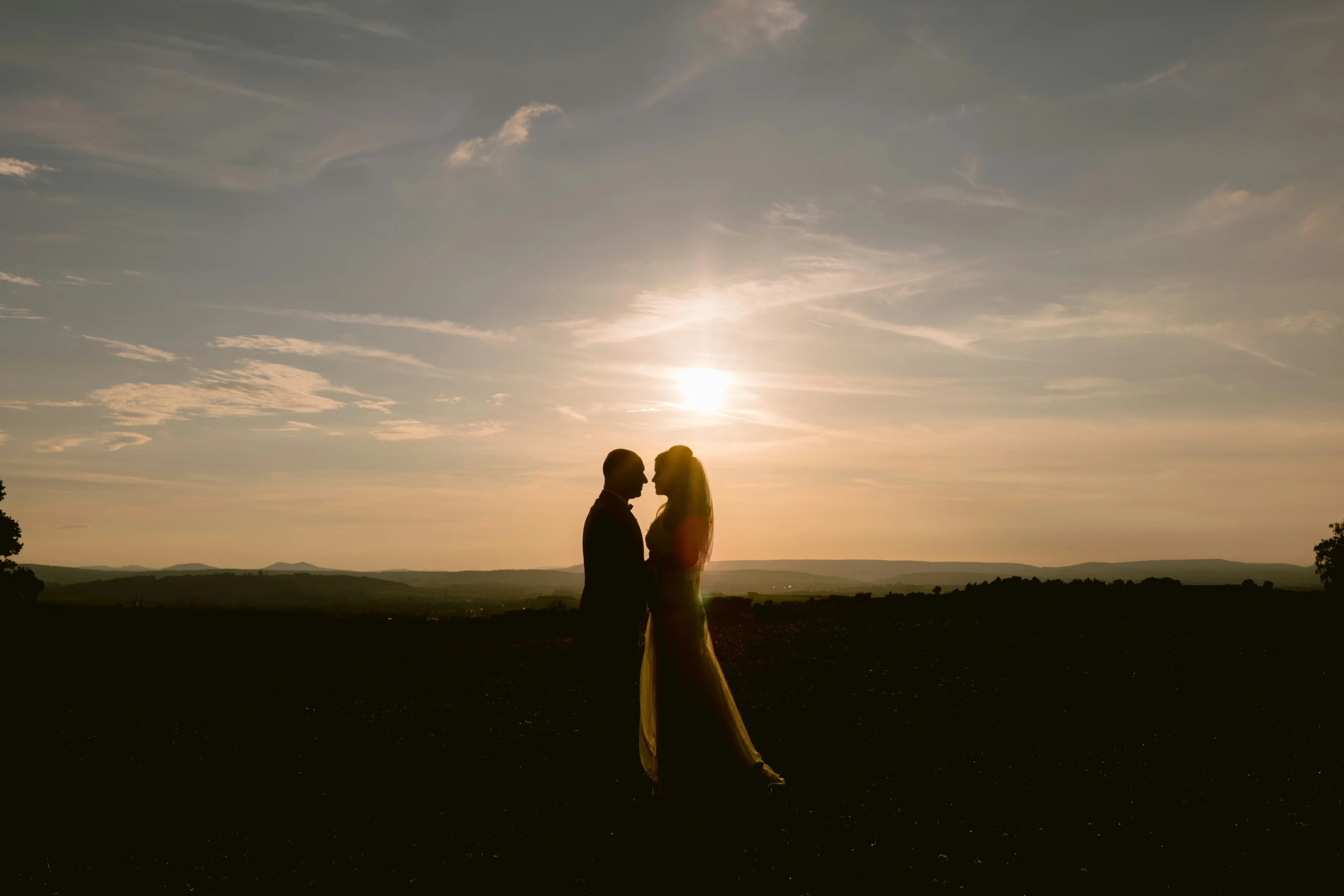 two people are emcing against the sunset in the field