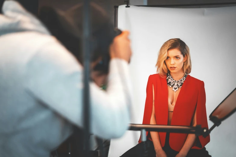 a model in a bright red jacket sitting by a lamp