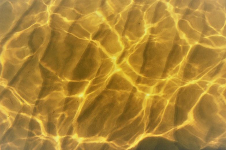 water ripples over sand and creates a gold color