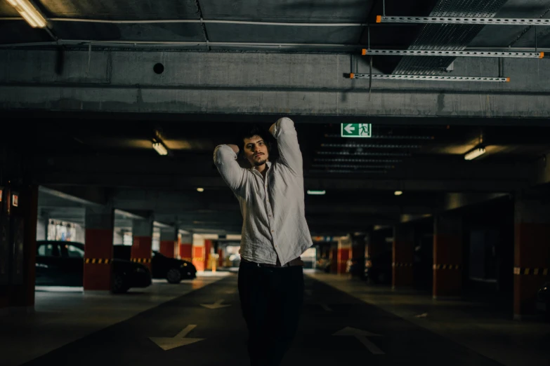 a man standing in a parking garage with his hands up