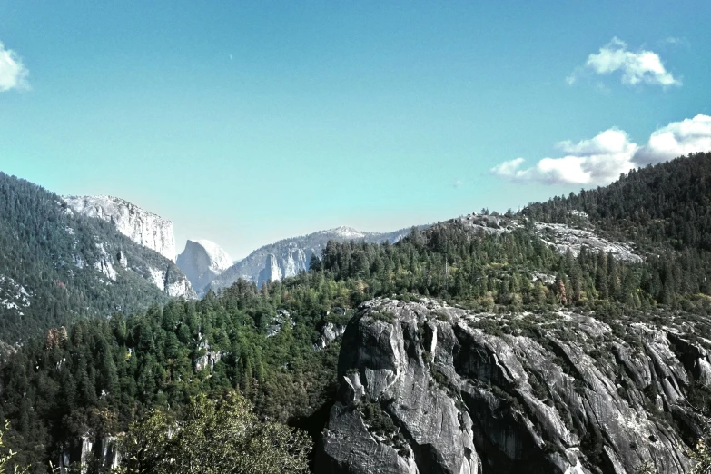 a mountain landscape with rock formations, trees and a blue sky