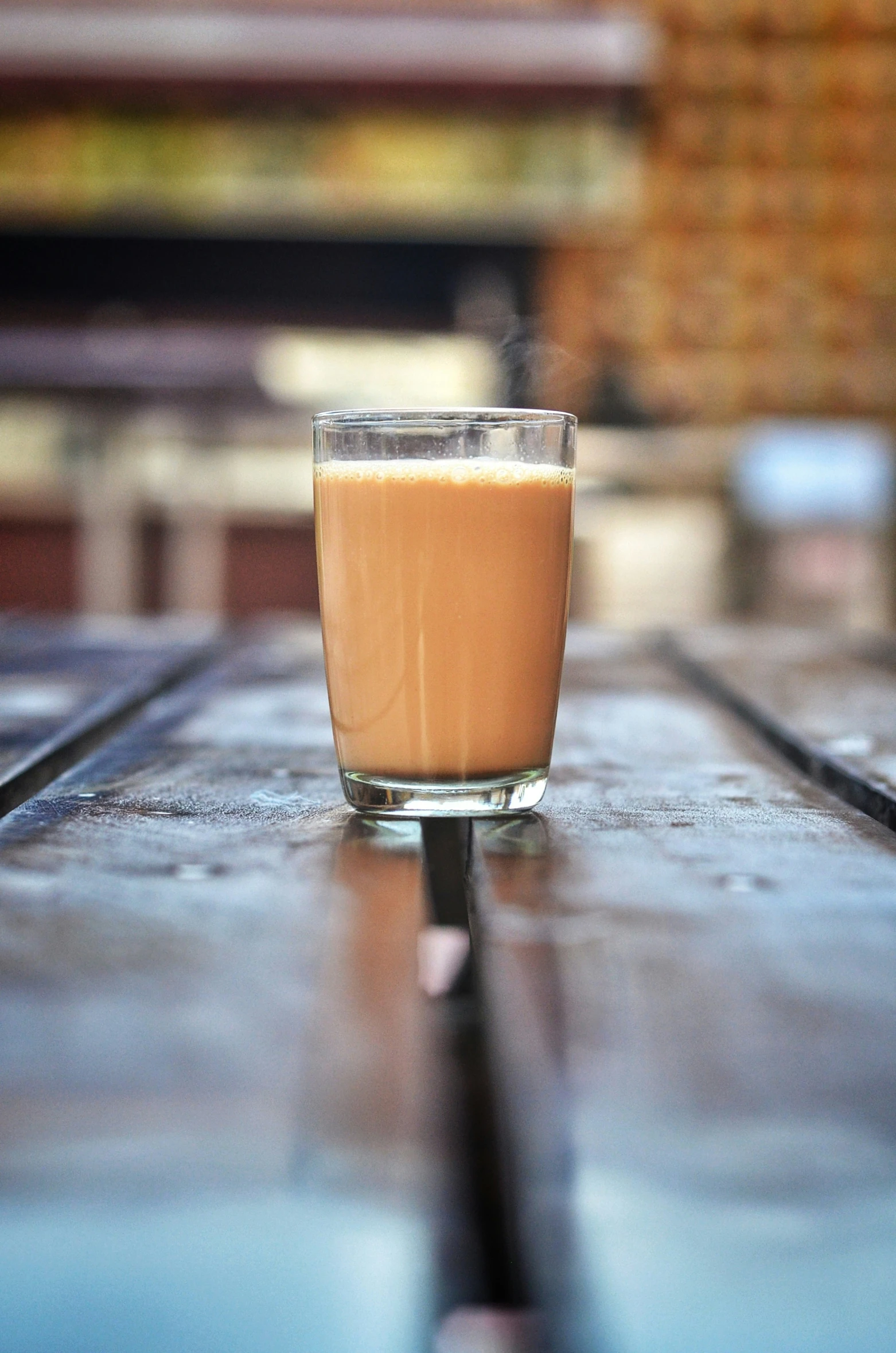 a glass on a table with the drink half empty