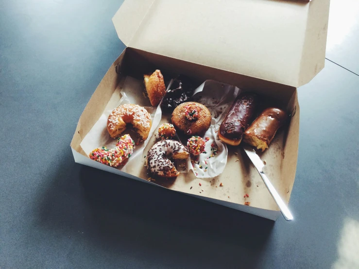 a box of donuts with sprinkles and a knife