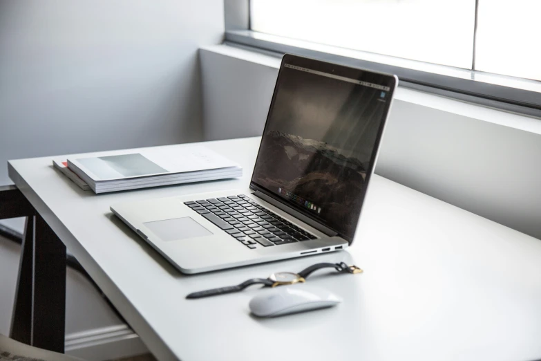 the laptop has a mouse on it next to an open book