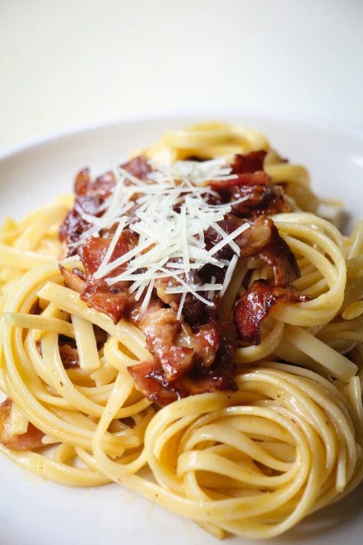 a close up of a plate of pasta with meat and grated cheese