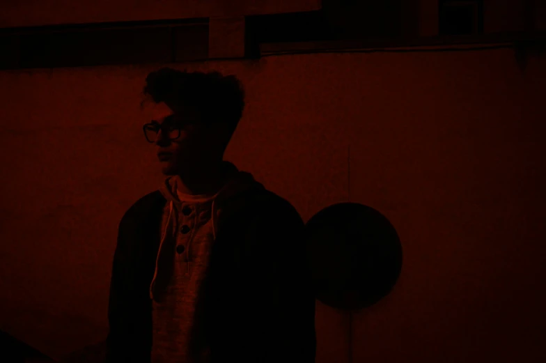 the man has glasses on and is standing in a dark room
