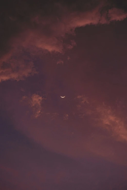 an airplane flying through a cloudy purple sky