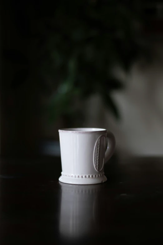 white cup sitting on top of a dark table