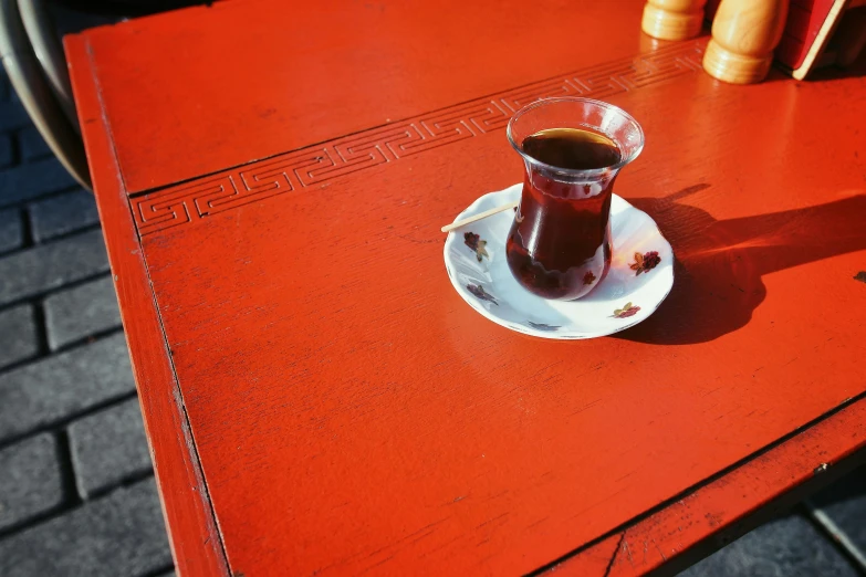 a small red table with a glass filled with soing