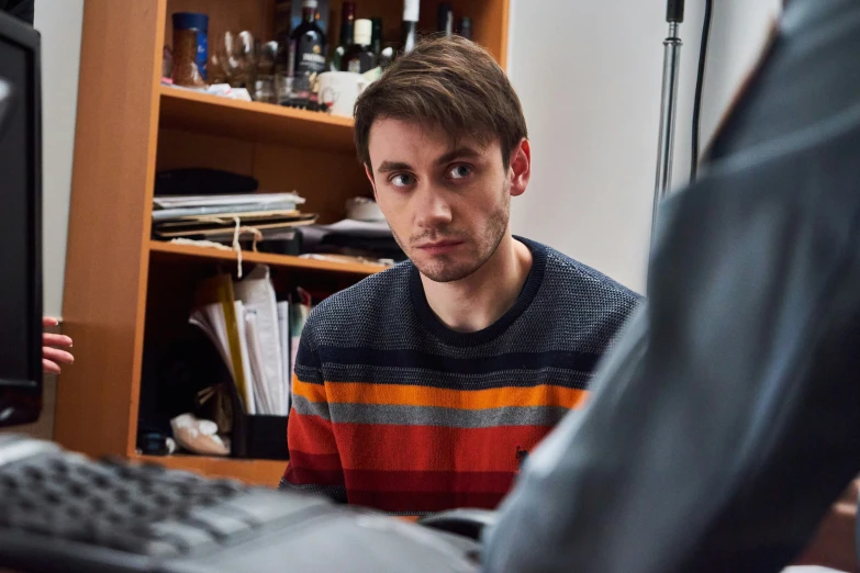 the young man in striped shirt is working on a computer