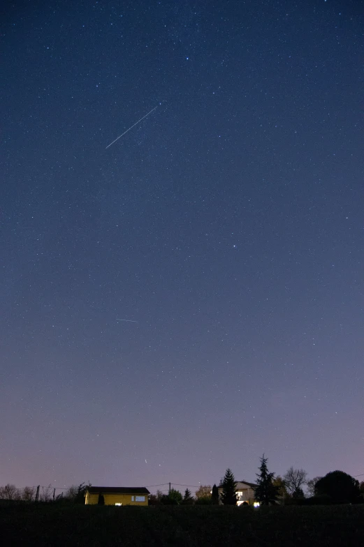 a night sky over some buildings with a streaky streak