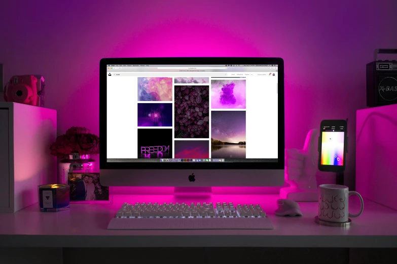 computer on pink lit desk in dim room