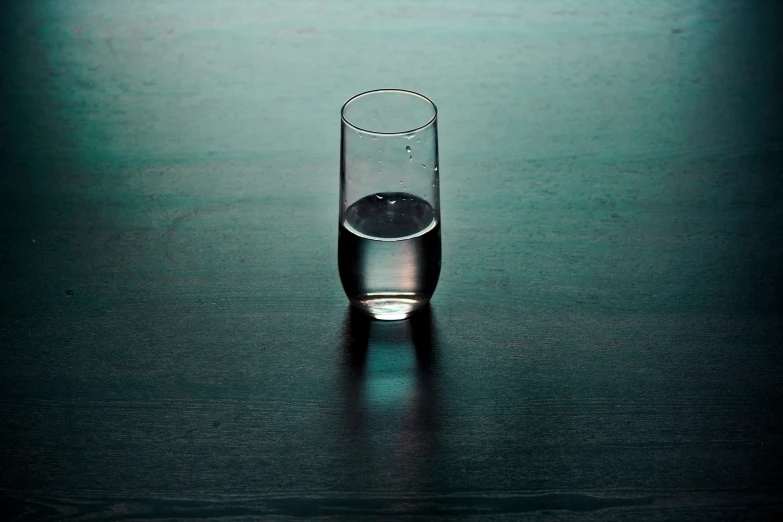 an empty glass on the ground on a black surface