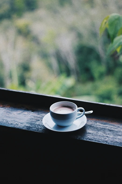 a coffee cup sitting on top of a wooden table next to a window