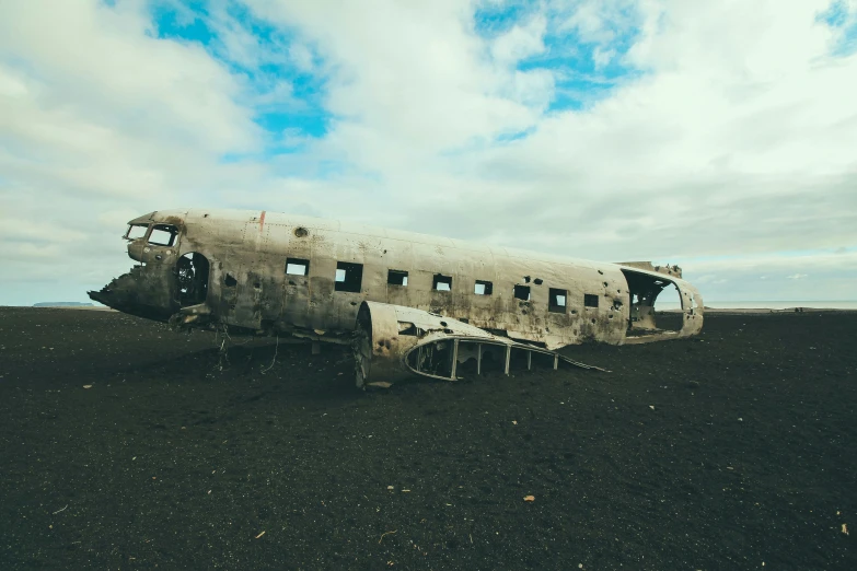 a large old, rusty, destroyed airplane sits on a plain