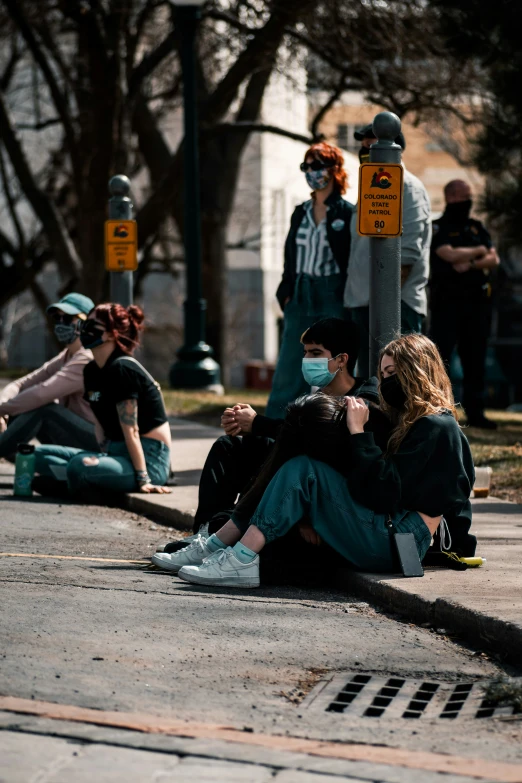 some people sitting on the ground and one has her hand around her neck