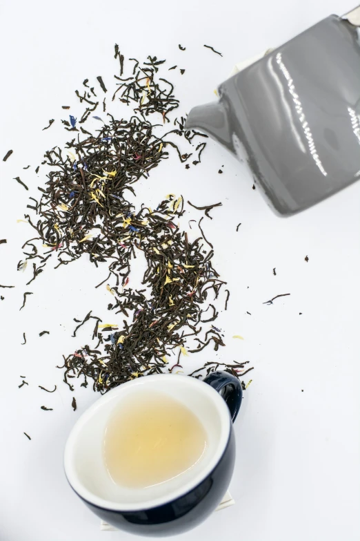 a cup of tea and the top of a teapot and the contents spilling about