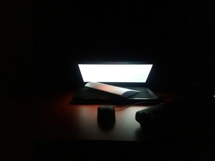 an illuminated laptop in the dark with a red light shining on it