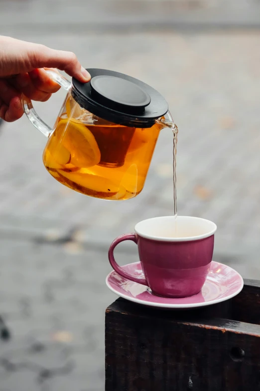 a hand is pouring tea into a cup