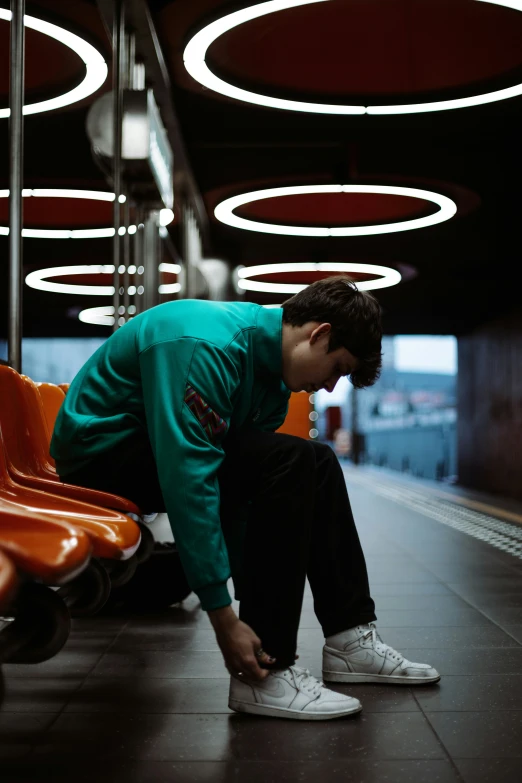 man with hat and green shirt sitting on orange seats