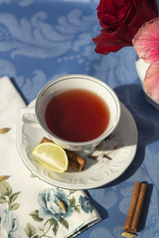 a tea cup, cinnamon sticks, and a flower on a table