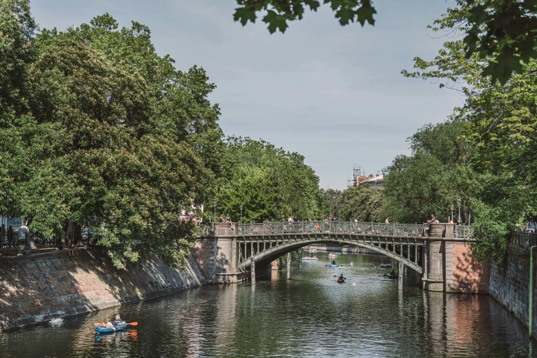 bridge over water with people rowing in small boats