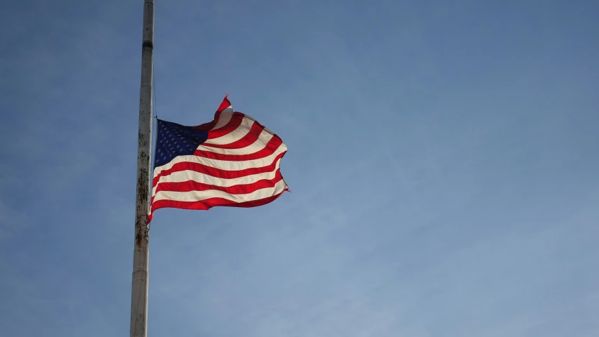 an american flag waving in the wind against a blue sky