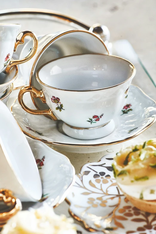 two tea cups and saucers on an ornate tablecloth